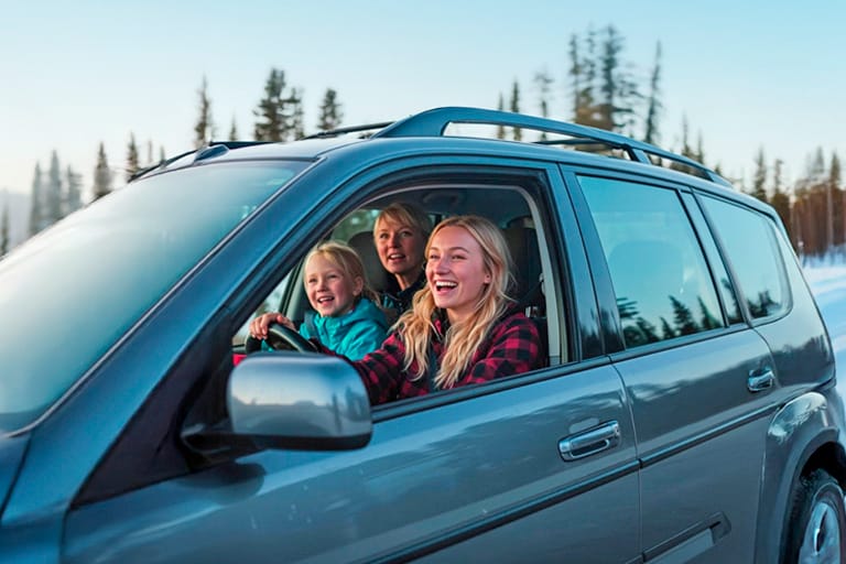 Iloisia lomalaisia autossa, etupenkillä nainen ja lapsi, takapenkillä nainen